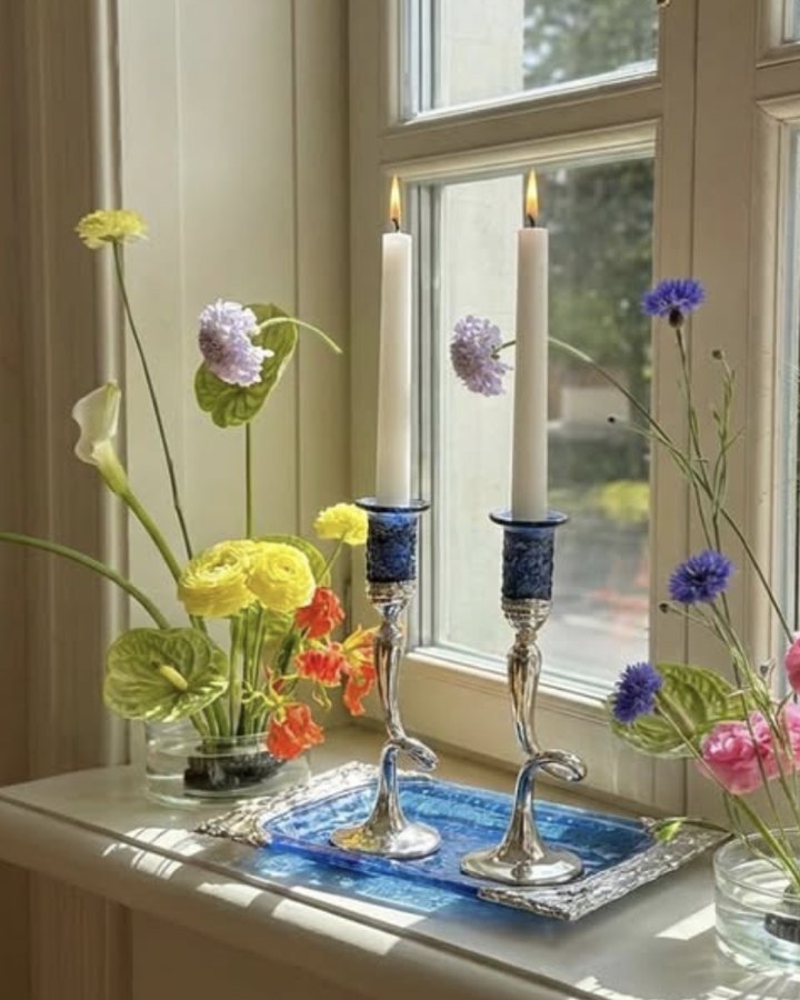 Silver and blue glass candlesticks on a sunny windowsill with spring flowers