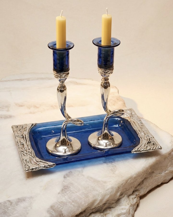 Silver and cobalt glass candlesticks on a tray, set on white stone