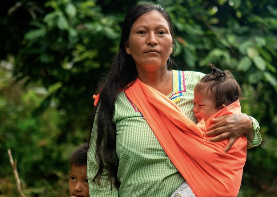 A Wiñak member holding her baby in an orange sling